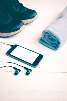 fitness equipment:running shoes,blue towel and smart phone on white wood table vintage style