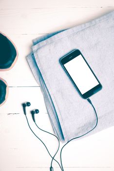 fitness equipment:running shoes,blue towel and smart phone on white wood table vintage style