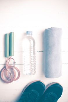 fitness equipment : running shoes,towel,jumping rope and drinking water on white wood table vintage style