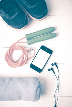 fitness equipment : running shoes,towel,jumping rope and phone on white wood table vintage style