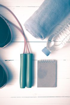 fitness equipment : running shoes,towel,jumping rope,water bottle and notepad on white wood table vintage style