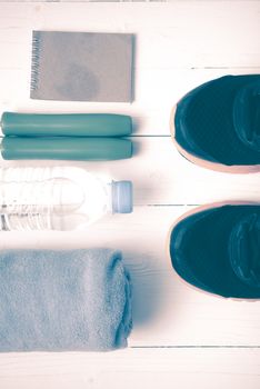 fitness equipment : running shoes,towel,jumping rope,water bottle and notepad on white wood table vintage style