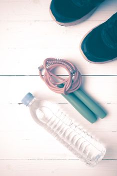 fitness equipment : running shoes,jumping rope and water bottle on white wood table vintage style