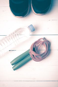 fitness equipment : running shoes,jumping rope and water bottle on white wood table vintage style