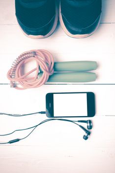 fitness equipment : running shoes,jumping rope and phone on white wood table vintage style