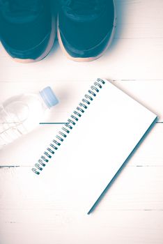 fitness equipment : running shoes,drinking water and notebook on white wood table vintage style