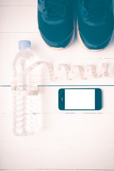 fitness equipment : running shoes,drinking water,measuring tape and phone on white wood table vintage style