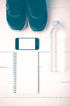 fitness equipment : running shoes,drinking water,notebook and phone on white wood table vintage style