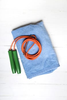 fitness equipment:blue towel,jumping rope on white wood table