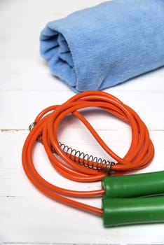 fitness equipment:blue towel,jumping rope on white wood table