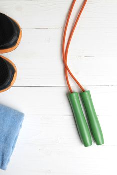 fitness equipment:blue towel,jumping rope and running shoes on white wood table
