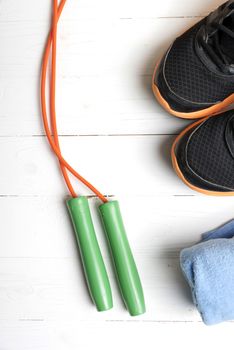 fitness equipment:blue towel,jumping rope and running shoes on white wood table