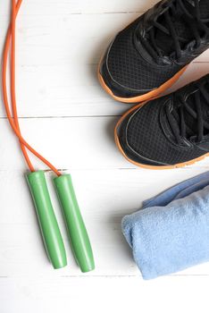fitness equipment:blue towel,jumping rope and running shoes on white wood table