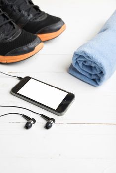 fitness equipment:running shoes,blue towel and smart phone on white wood table