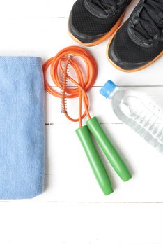 fitness equipment : running shoes,towel,jumping rope and drinking water on white wood table