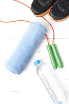 fitness equipment : running shoes,towel,jumping rope and drinking water on white wood table