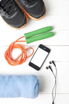 fitness equipment : running shoes,towel,jumping rope and phone on white wood table
