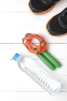 fitness equipment : running shoes,jumping rope and water bottle on white wood table