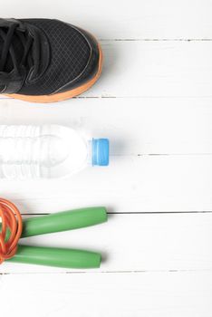 fitness equipment : running shoes,jumping rope and water bottle on white wood table