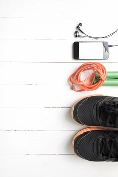 fitness equipment : running shoes,jumping rope and phone on white wood table