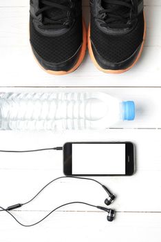 fitness equipment : running shoes,drinking water and phone on white wood table