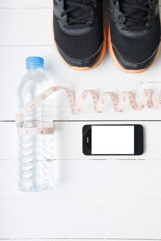 fitness equipment : running shoes,drinking water,measuring tape and phone on white wood table