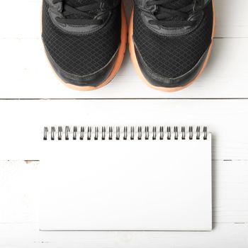 running shoes and notepad on white wood table