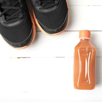 running shoes and orange juice on white wood table