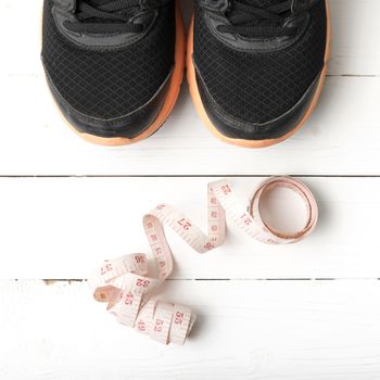 running shoes and measuring tape on white wood table