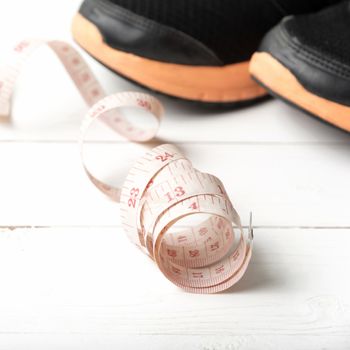 running shoes and measuring tape on white wood table