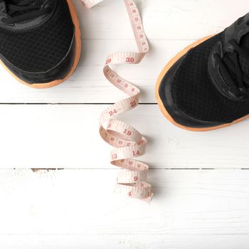 running shoes and measuring tape on white wood table