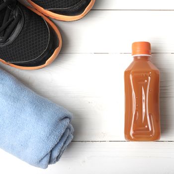 running shoes,towel and orange juice on white wood table