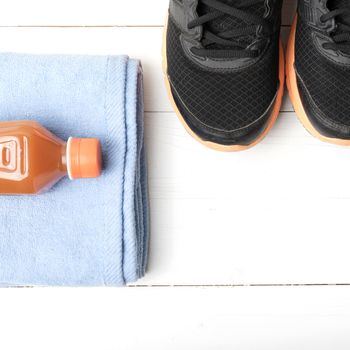 running shoes,towel and orange juice on white wood table