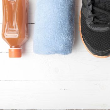 running shoes,towel and orange juice on white wood table