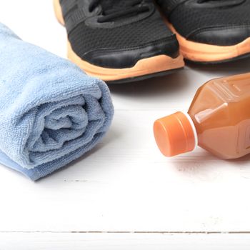running shoes,towel and orange juice on white wood table