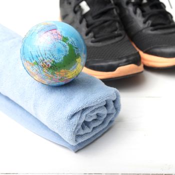 running shoes,towel and earth ball on white wood table concept world healthy