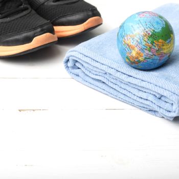 running shoes,towel and earth ball on white wood table concept world healthy