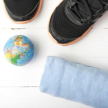 running shoes,towel and earth ball on white wood table concept world healthy