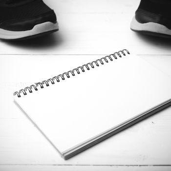 running shoes and notepad on white wood table black and white tone color style