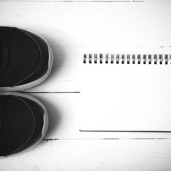 running shoes and notepad on white wood table black and white tone color style
