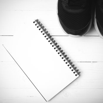running shoes and notepad on white wood table black and white tone color style