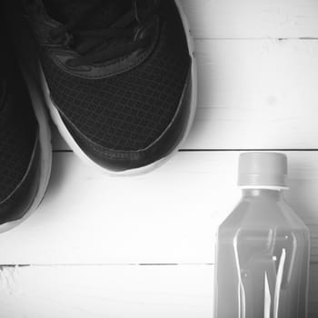 running shoes and orange juice on white wood table black and white tone color style