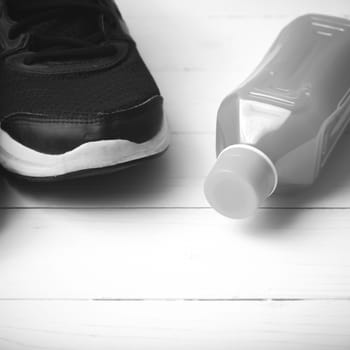 running shoes and orange juice on white wood table black and white tone color style