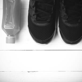 running shoes and orange juice on white wood table black and white tone color style