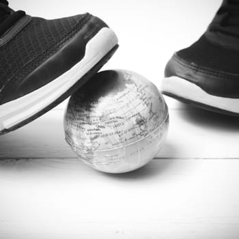 running shoes and earth ball on white wood table concept world healthy black and white tone color style