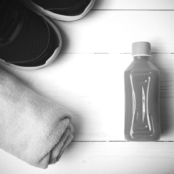 running shoes,towel and orange juice on white wood table black and white tone color style