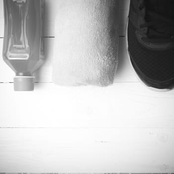 running shoes,towel and orange juice on white wood table black and white tone color style