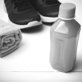 running shoes,towel and orange juice on white wood table black and white tone color style