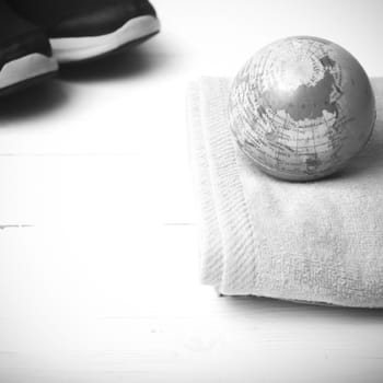 running shoes,towel and earth ball on white wood table concept world healthy black and white tone color style