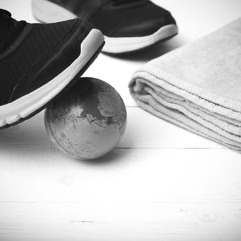 running shoes,towel and earth ball on white wood table concept world healthy black and white tone color style